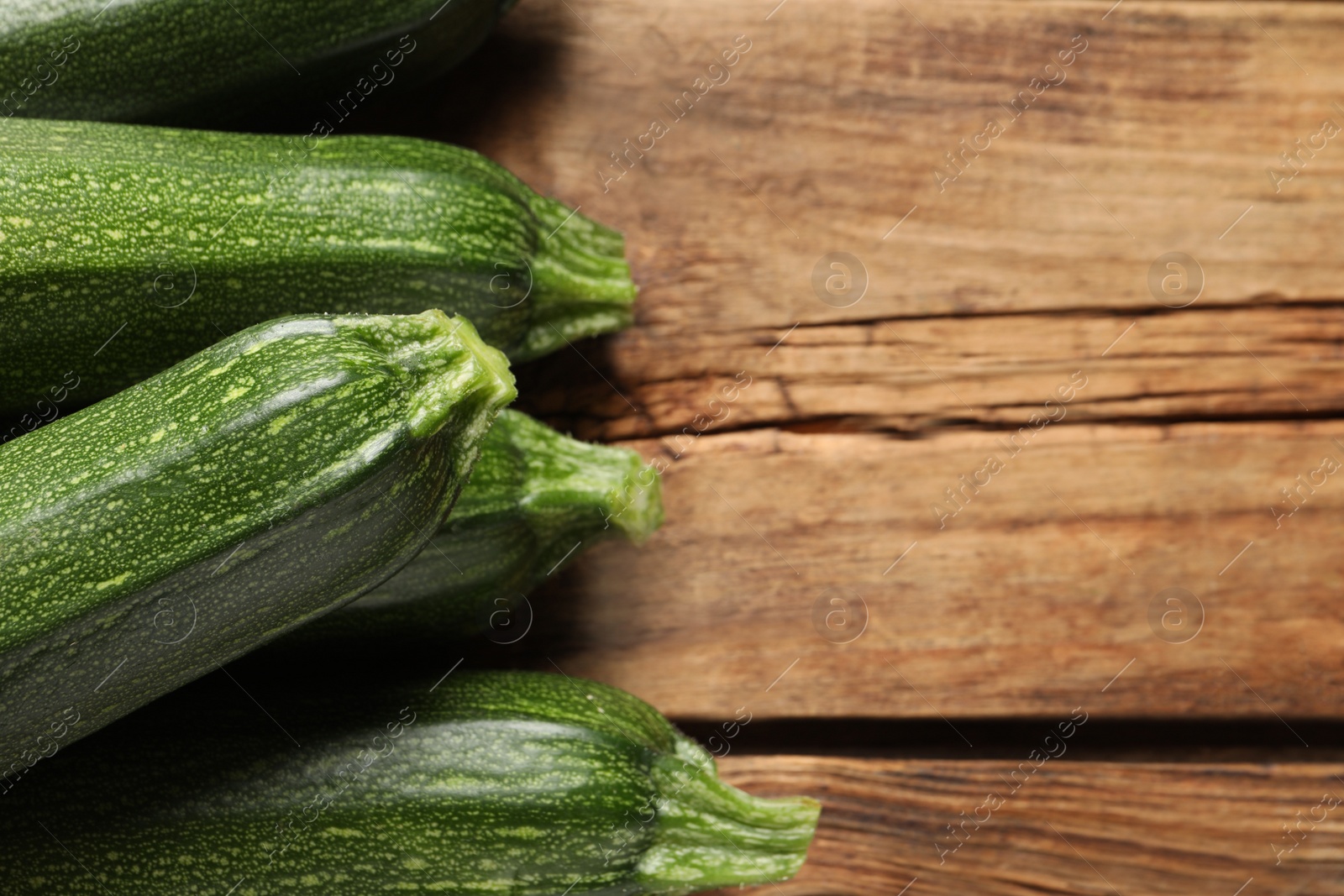 Photo of Raw ripe zucchinis on wooden table, closeup. Space for text