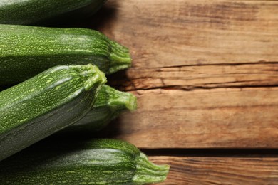 Photo of Raw ripe zucchinis on wooden table, closeup. Space for text