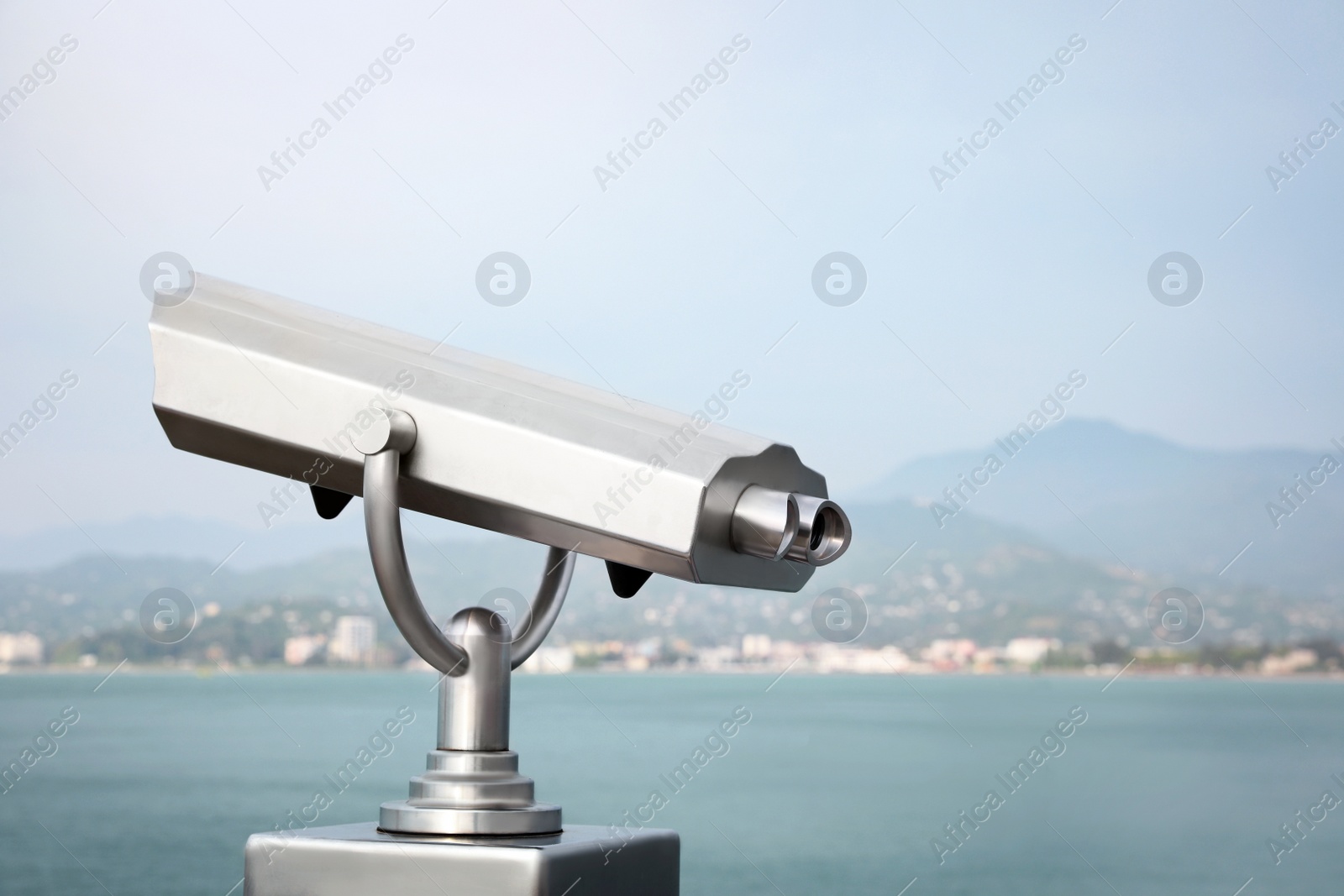 Photo of Metal tower viewer installed near sea, space for text. Mounted binoculars