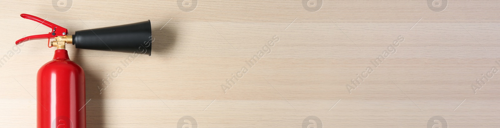 Image of Fire extinguisher on wooden background, top view with space for text. Banner design