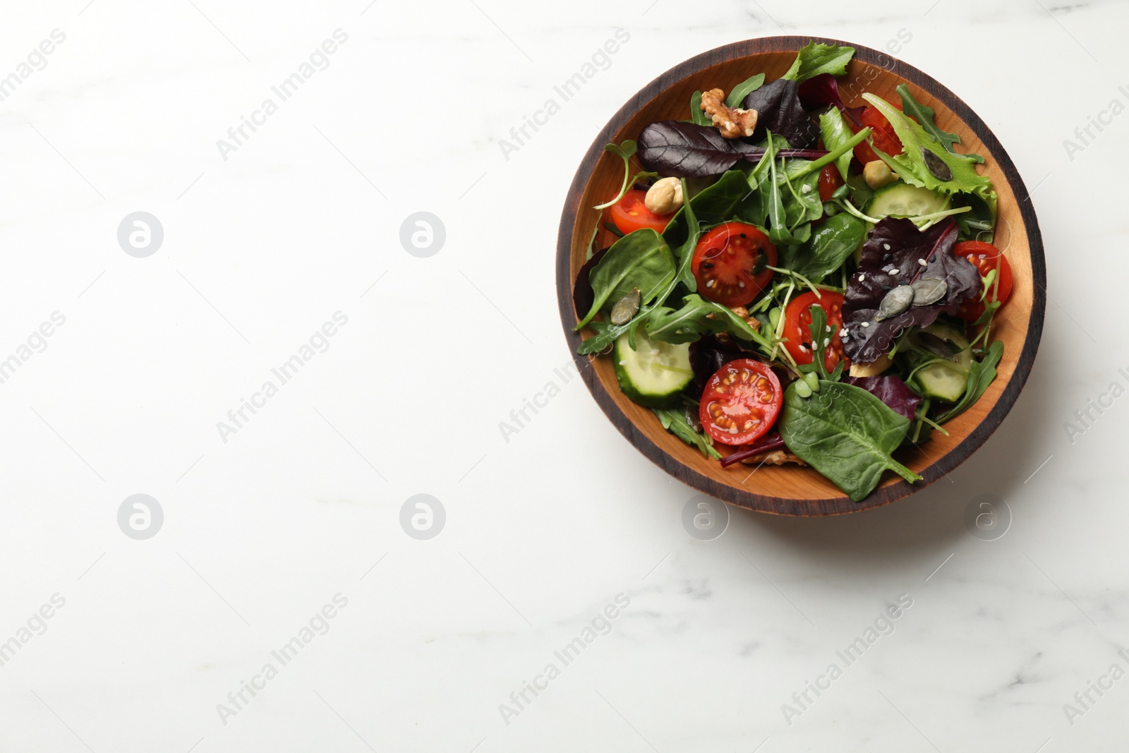 Photo of Tasty fresh vegetarian salad on white marble table, top view. Space for text