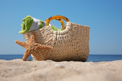 Bag with beach accessories on sand near sea