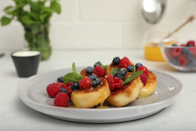 Photo of Delicious cottage cheese pancakes with fresh berries and mint on white table