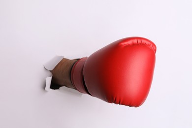 Photo of Man breaking through white paper with boxing glove, closeup