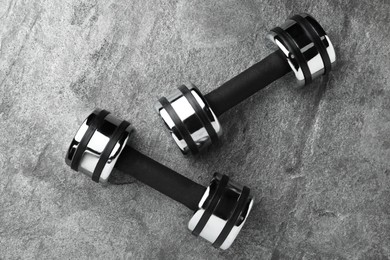 Photo of Two dumbbells on grey background, flat lay