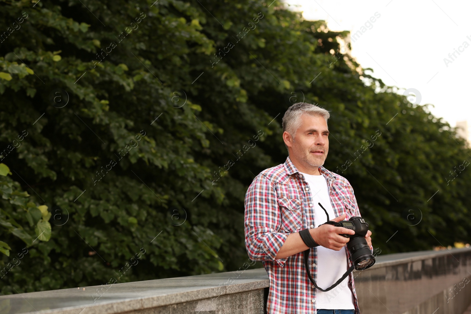 Photo of Handsome mature man with professional camera outdoors. Space for text