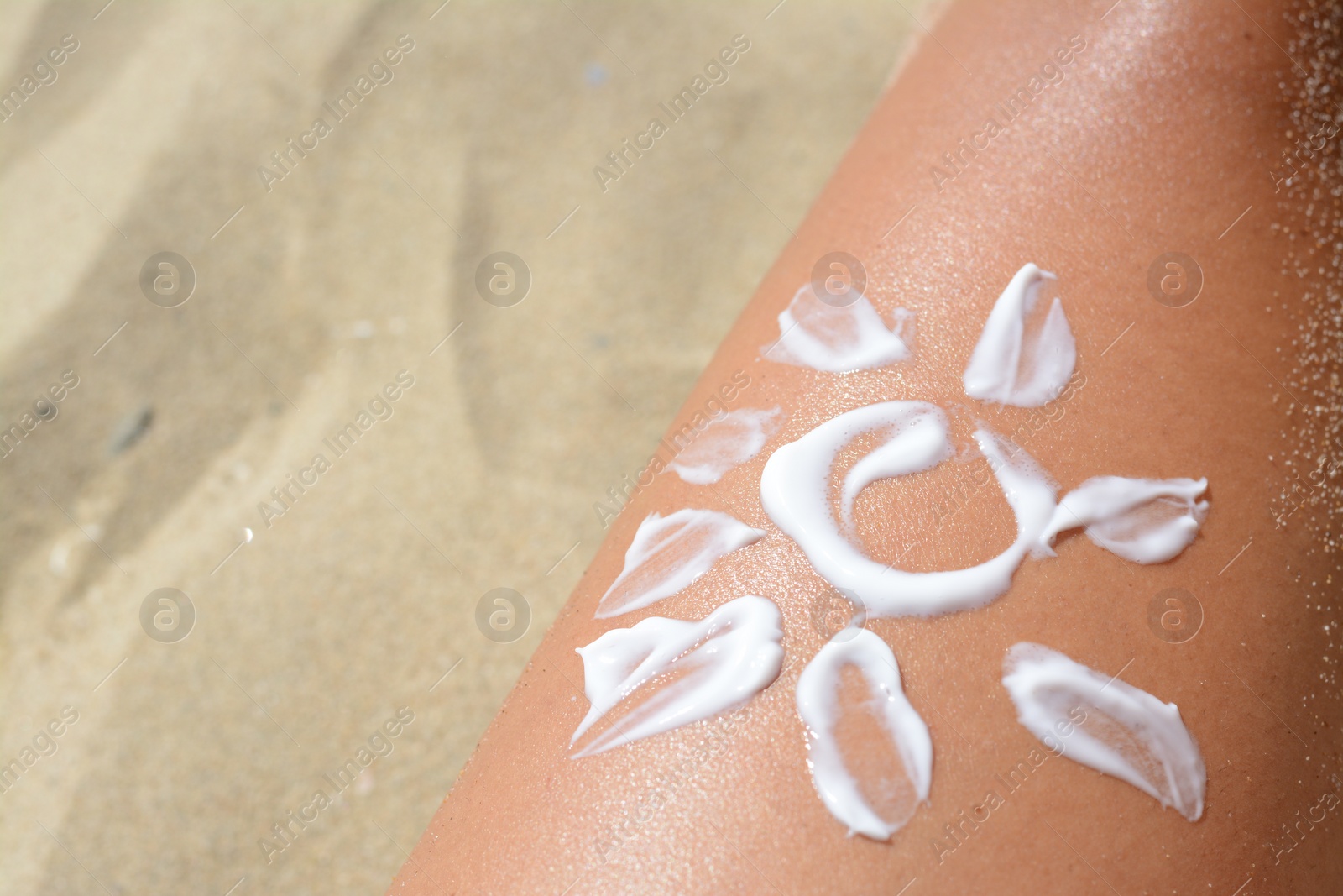 Photo of Sun drawn with sunscreen on woman's leg at beach, closeup. Space for text