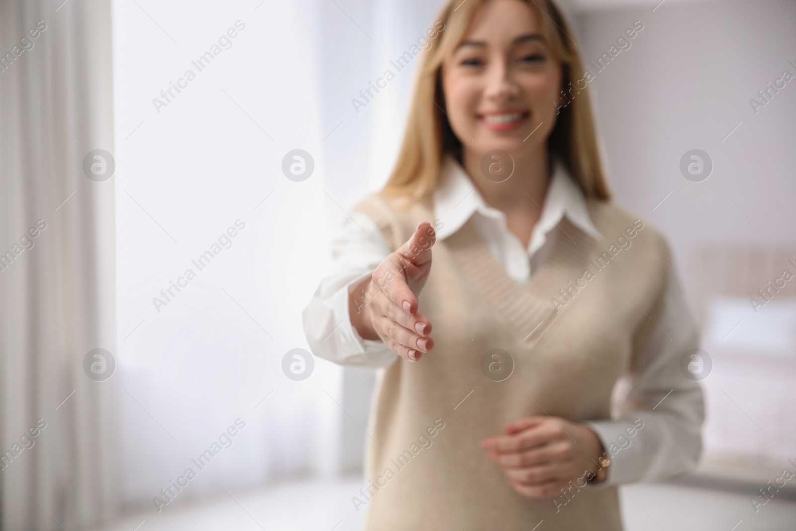 Photo of Happy young woman offering handshake indoors. Space for text