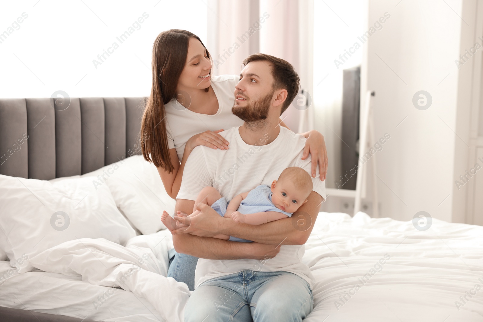 Photo of Happy family. Parents with their cute baby on bed indoors