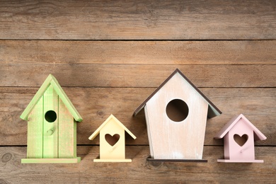 Collection of handmade bird houses on wooden background, flat lay