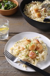 Delicious scallop pasta with onion served on wooden table