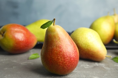 Photo of Ripe juicy pears on grey stone table against blue background