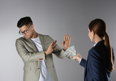 Photo of Man refusing to take bribe on grey background