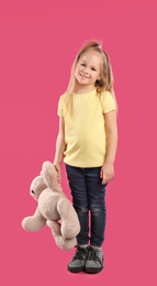 Little girl with teddy bear on pink background