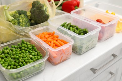 Photo of Plastic and glass containers with different fresh products on white countertop, closeup