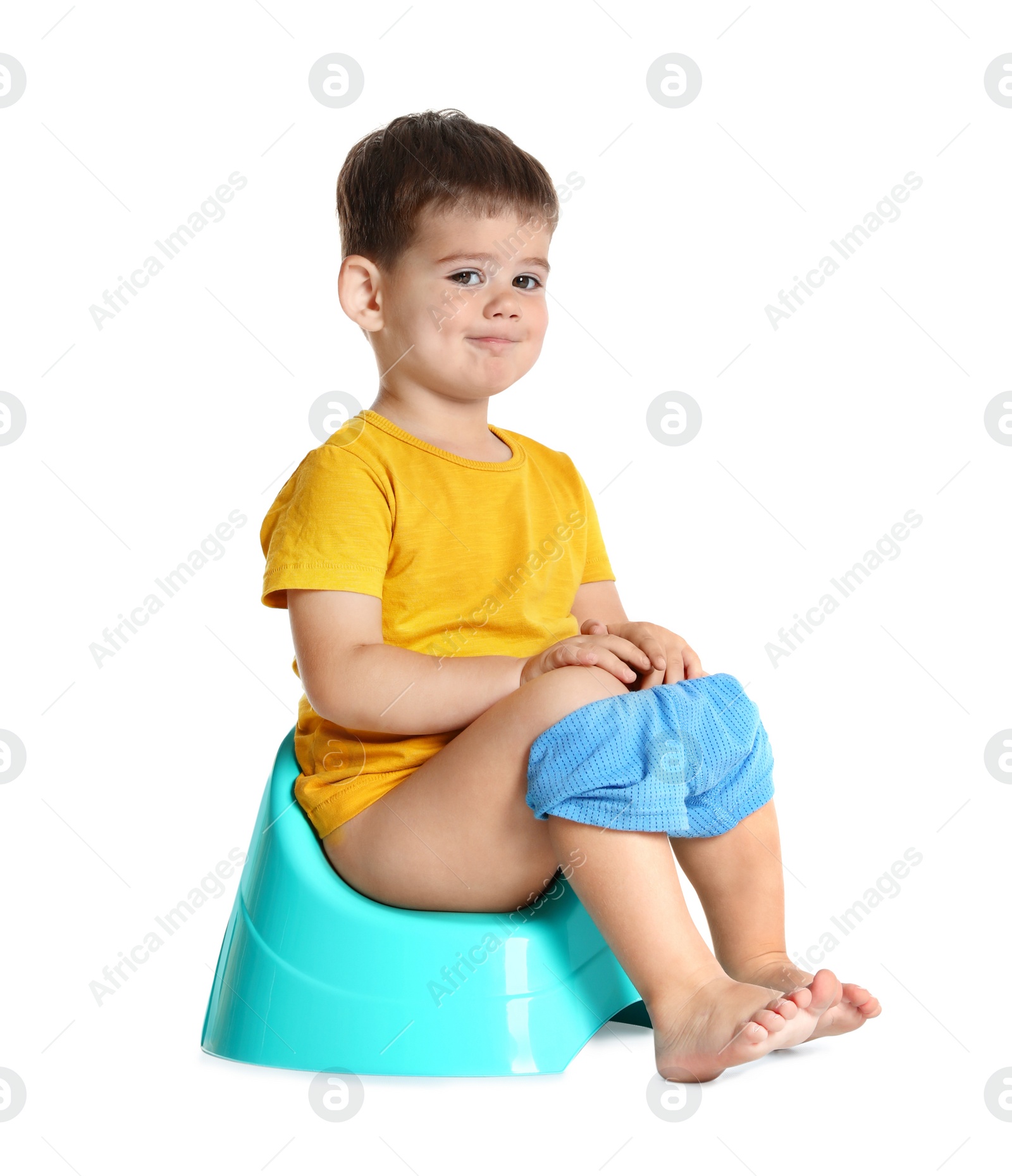 Photo of Portrait of little boy sitting on potty against white background