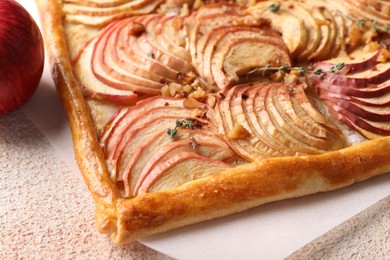 Photo of Freshly baked apple pie with nuts on beige textured table, closeup