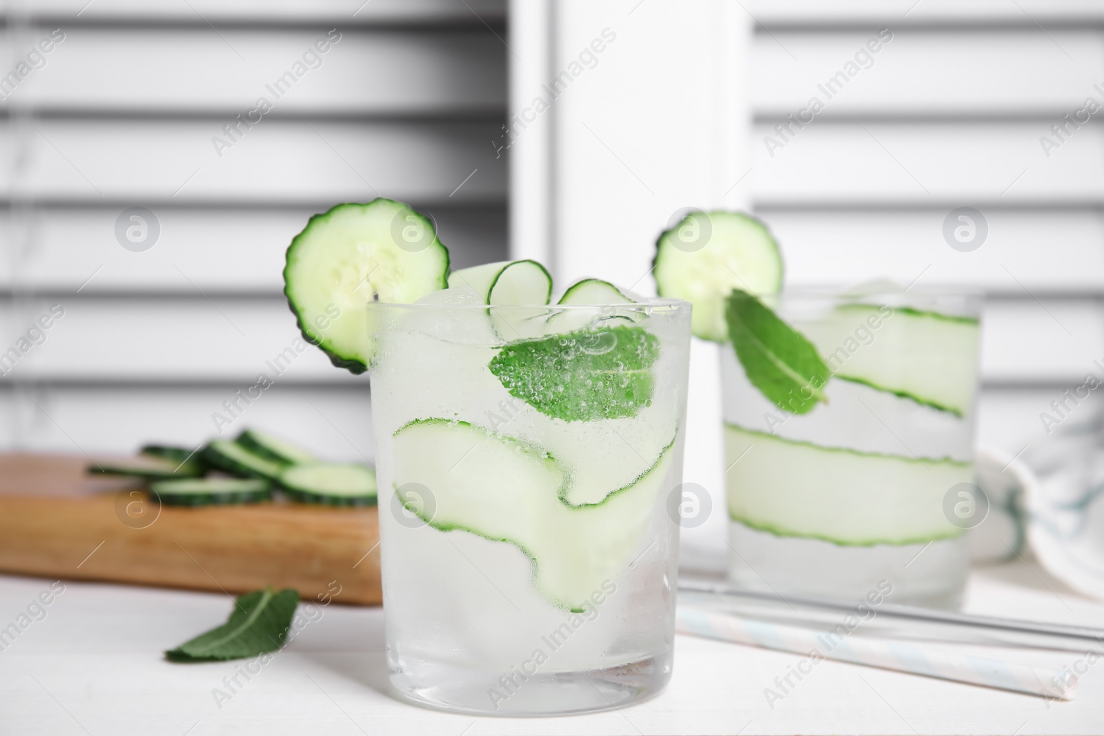 Photo of Tasty fresh cucumber water with mint on white wooden table