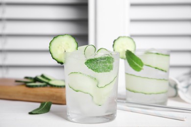 Photo of Tasty fresh cucumber water with mint on white wooden table