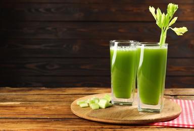 Photo of Celery juice and fresh vegetables on wooden table, space for text