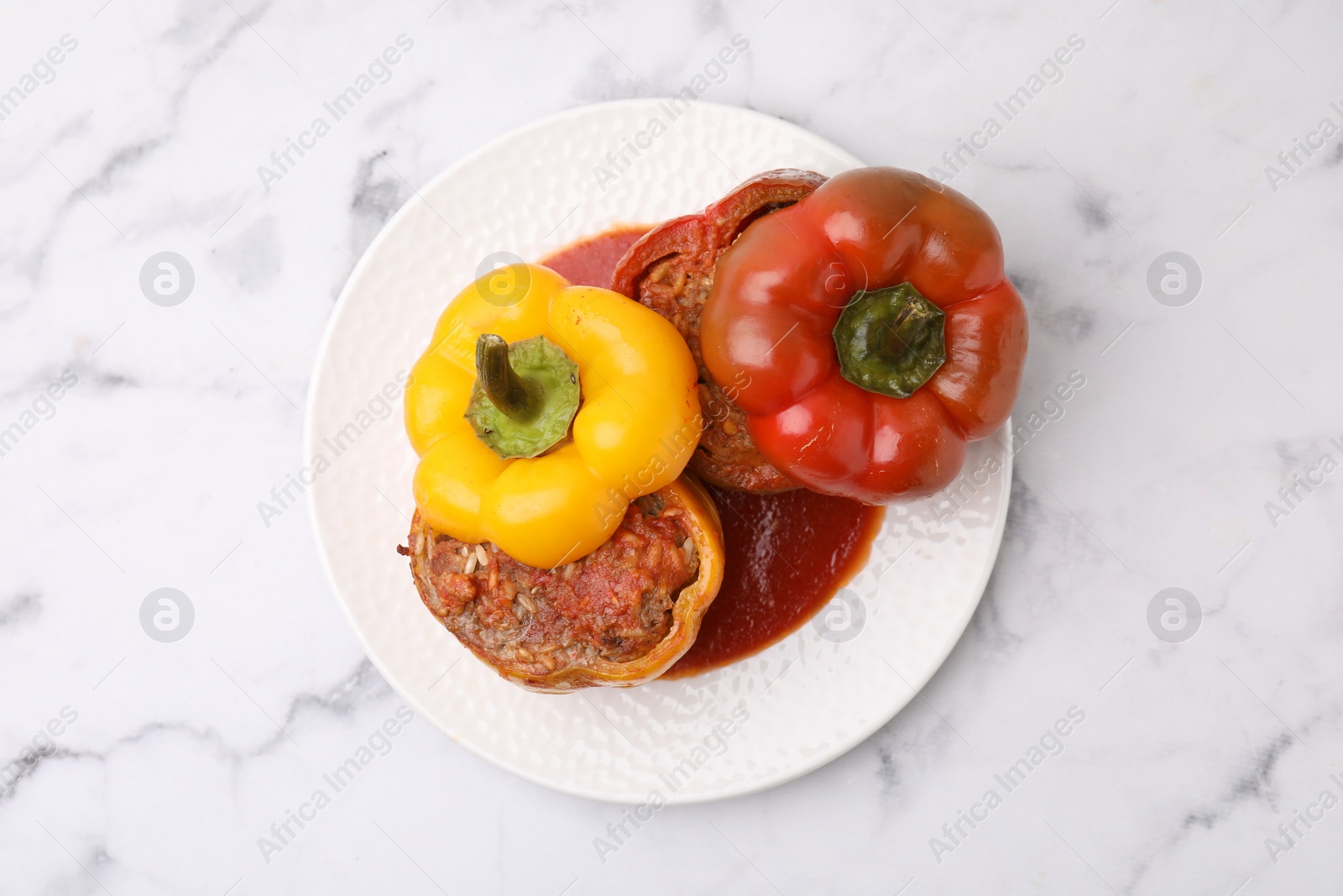 Photo of Delicious stuffed bell peppers served on white marble table, top view