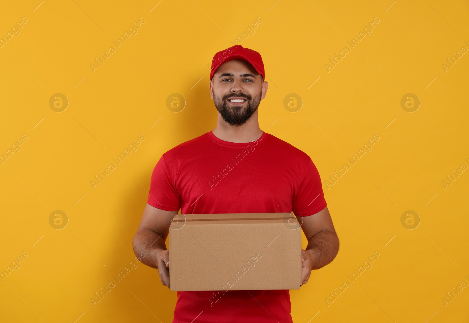 Photo of Courier holding cardboard box on yellow background