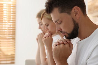 Photo of Group of religious people praying together indoors. Space for text