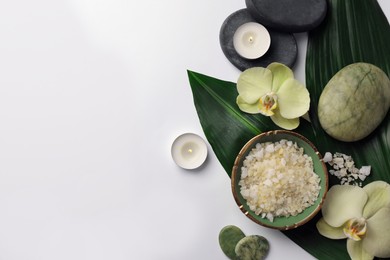 Flat lay composition with spa stones, sea salt and beautiful flowers on white table. Space for text