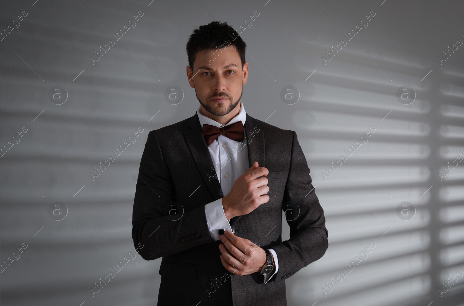 Photo of Man wearing stylish suit and cufflinks near white wall