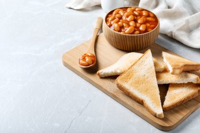 Photo of Toasts and delicious canned beans on white table, space for text
