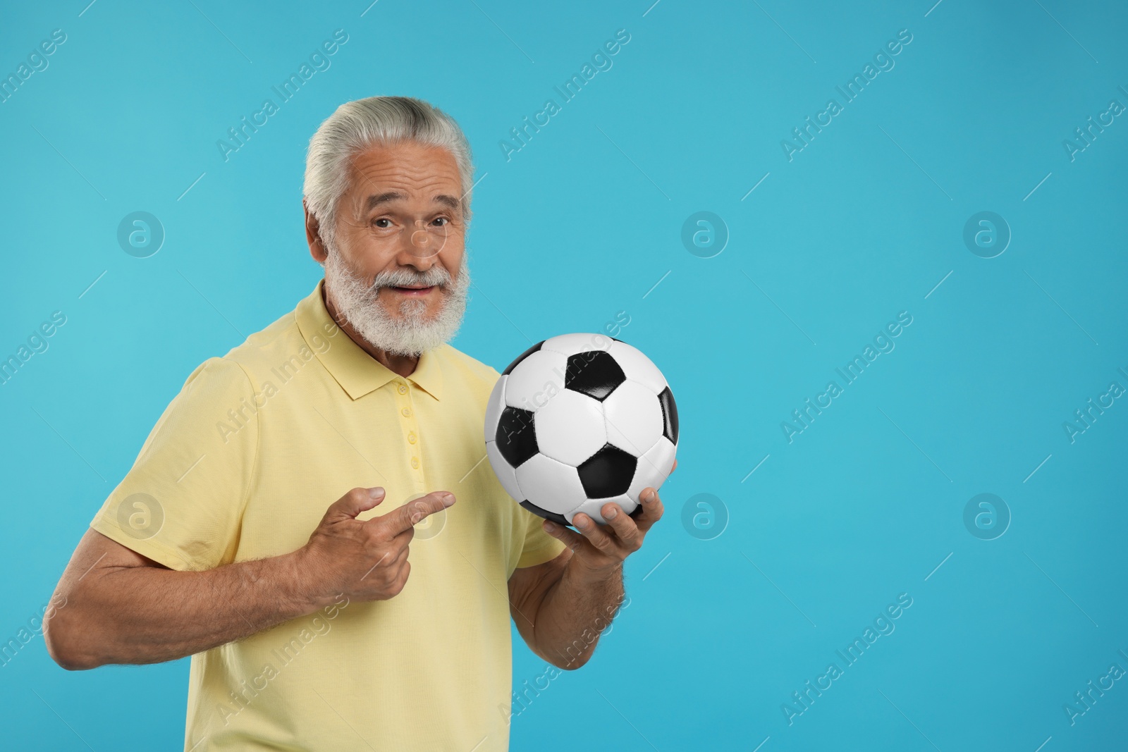 Photo of Senior sports fan with soccer ball on light blue background, space for text