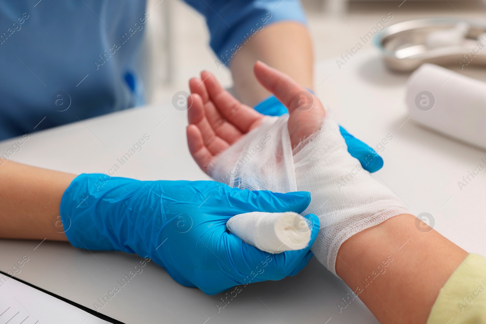 Photo of Doctor bandaging patient's burned hand indoors, closeup