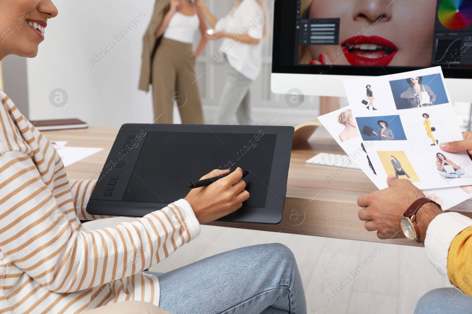 Photo of Professional retoucher working with graphic tablet at desk in photo studio, closeup