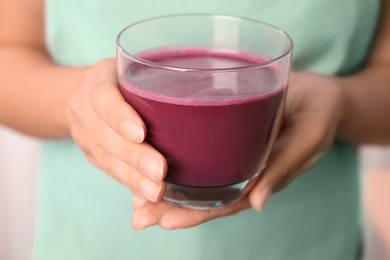 Woman holding glass of delicious acai juice, closeup