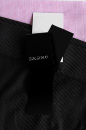 Photo of Clothing label with care information on black garment, top view