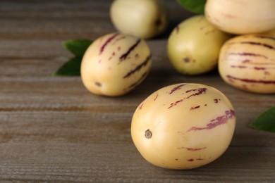 Fresh ripe pepino melons on wooden table, space for text