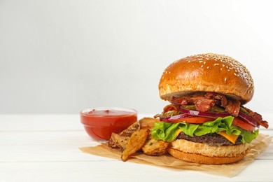 Tasty burger, potato wedges and sauce on white wooden table, space for text. Fast food