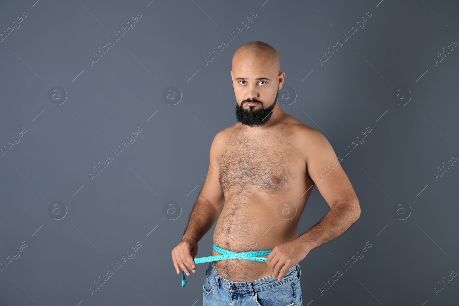 Photo of Overweight man with measuring tape on gray background