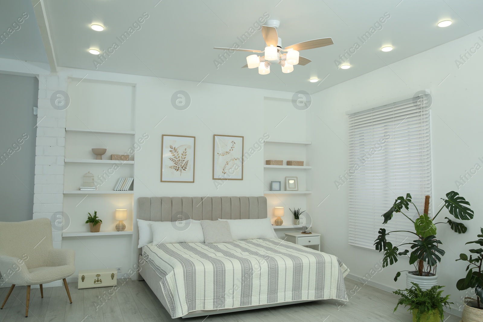 Photo of Comfortable furniture, ceiling fan, houseplants and accessories in stylish bedroom