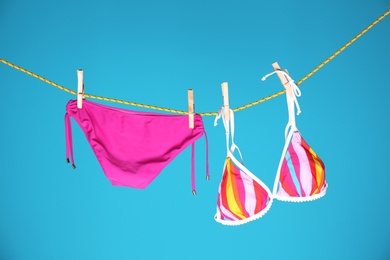 Photo of Beautiful bikini hanging on rope against color background