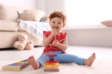 Photo of Cute little child playing with toys on floor at home