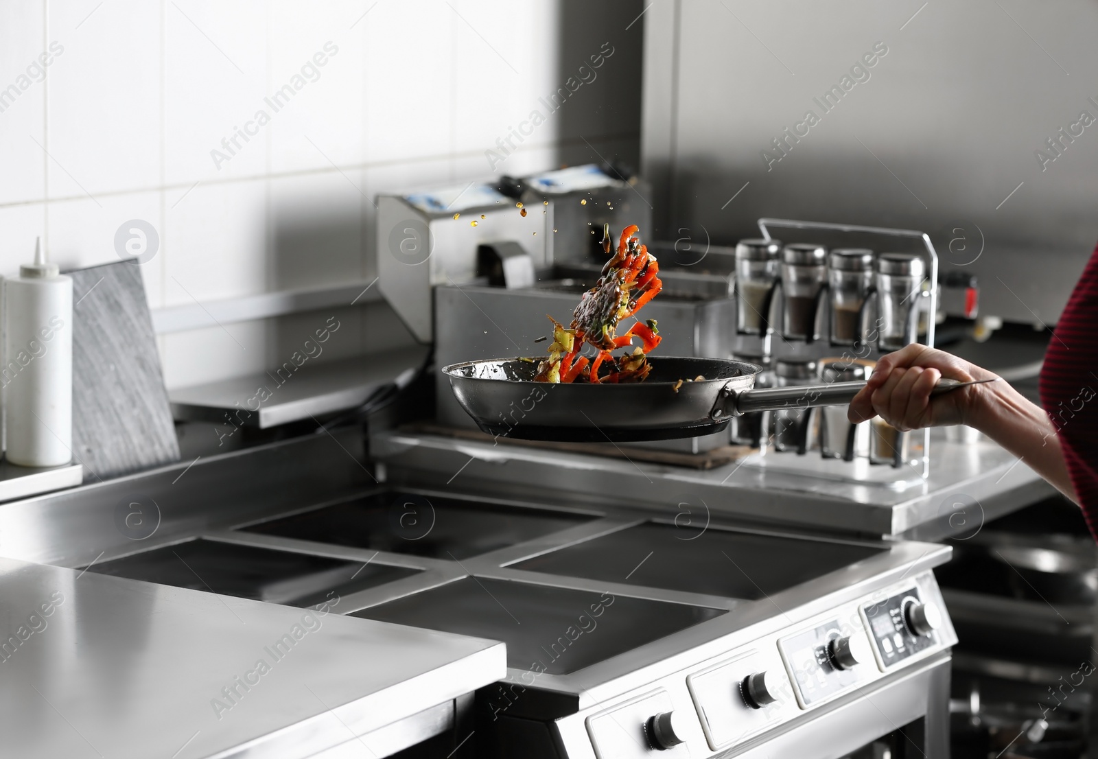 Photo of Woman cooking tasty food on stove in restaurant  kitchen, closeup
