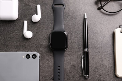 Photo of Flat lay composition with stylish smart watch on grey stone table