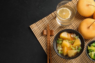 Photo of Bowl of tasty turnip soup served on black table, flat lay. Space for text