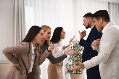 Photo of Group of angry coworkers quarreling in office