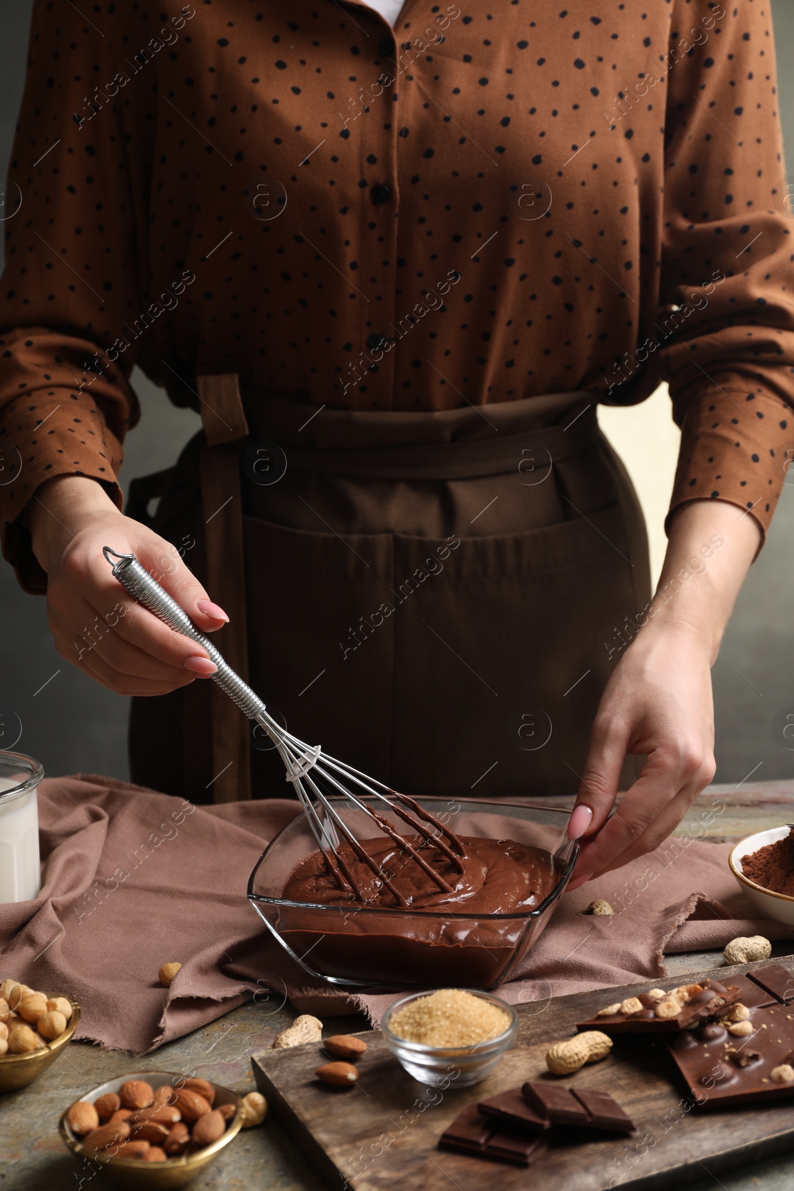 Photo of Woman mixing delicious chocolate cream with whisk at table, closeup