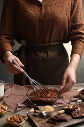 Photo of Woman mixing delicious chocolate cream with whisk at table, closeup