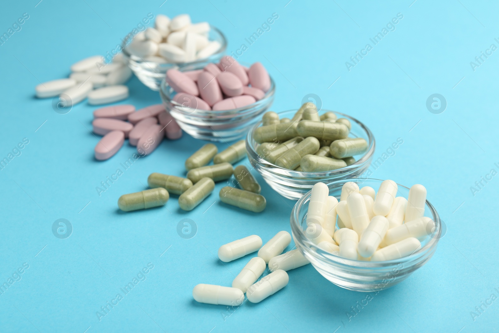 Photo of Different vitamin pills on light blue background