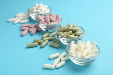 Photo of Different vitamin pills on light blue background