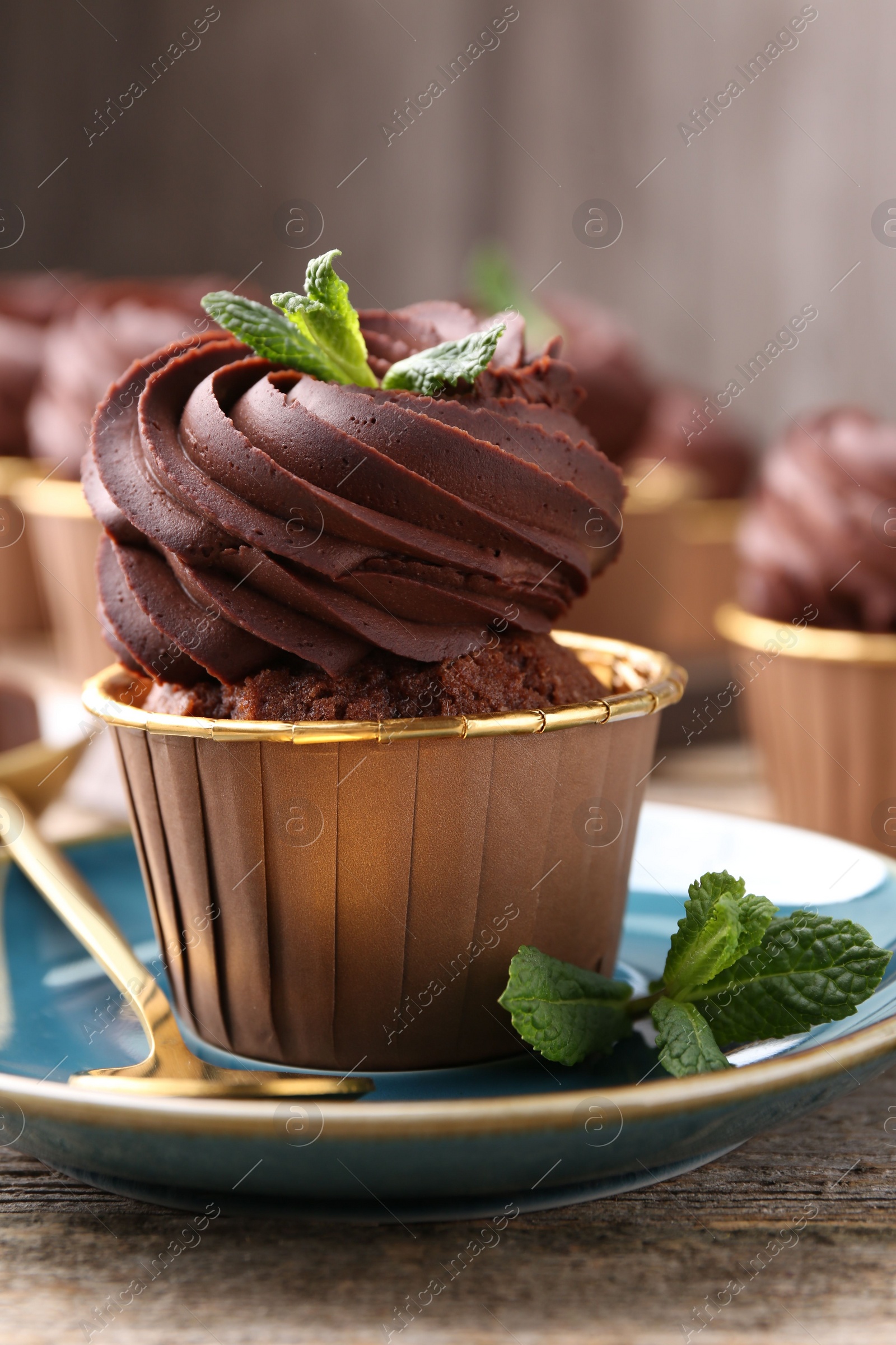 Photo of Delicious chocolate cupcake with mint on wooden table, closeup